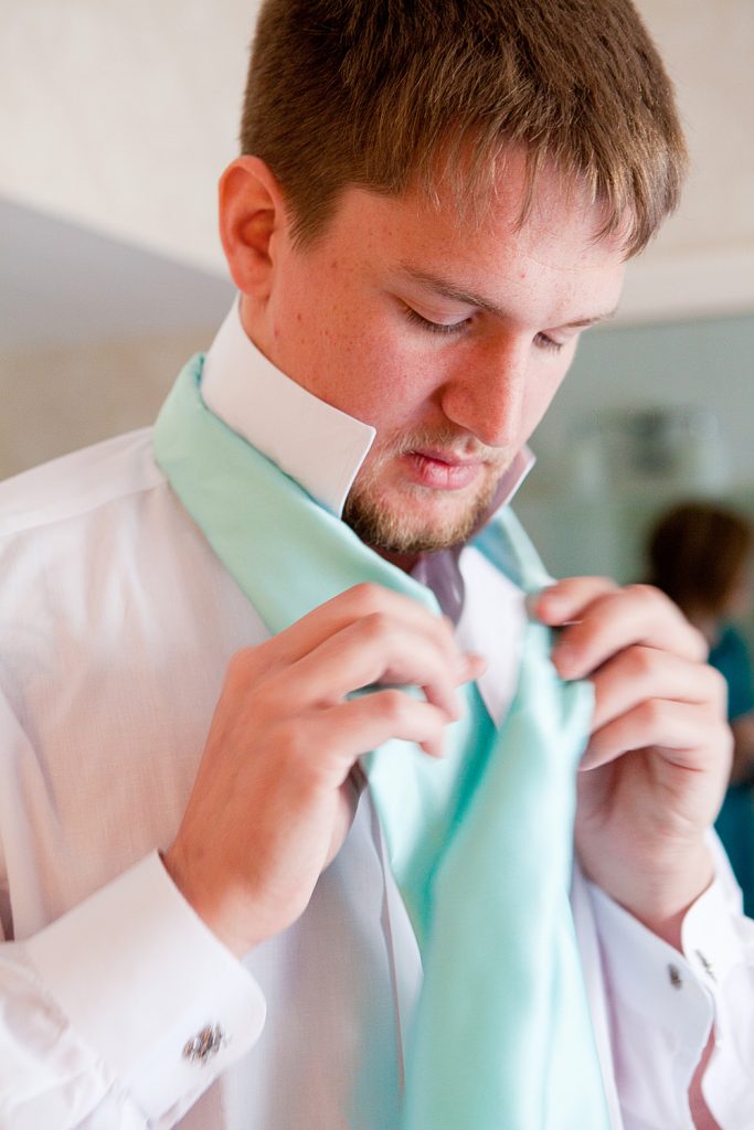The groom putting on his tie