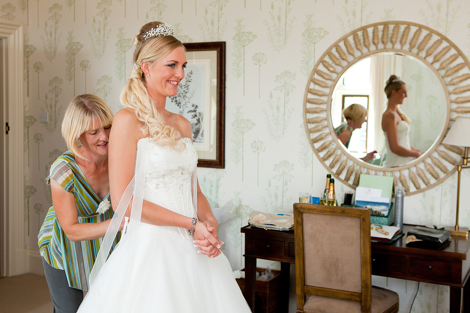 Bride's mother assisting her daughter into her wedding dress. 
