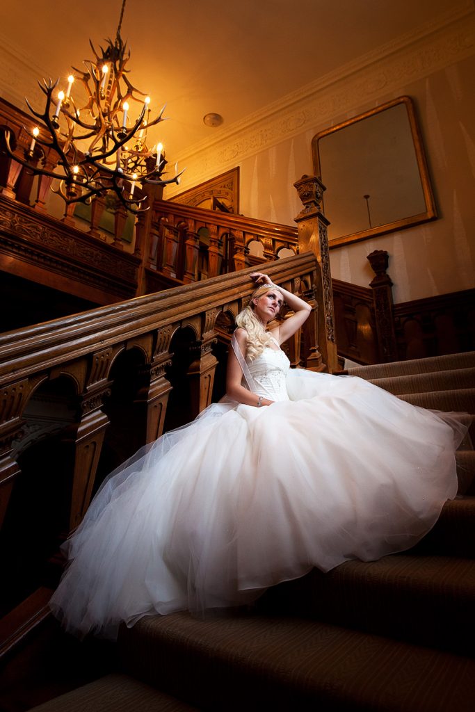 Stunning Bride sat on the incredible staircase on her wedding day at Bovey Castle on Dartmoor in the heart of Devon. 